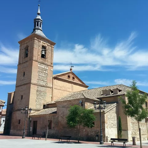 Iglesia de piedra con torre campanario en plaza abierta