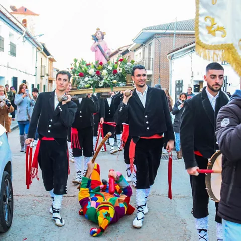 Procesión con imagen religiosa por una calle del pueblo.