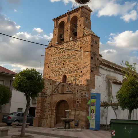 Iglesia de piedra y ladrillo con torre campanario