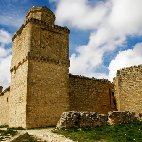 Fortaleza de piedra sobre colina con cielo parcialmente nublado