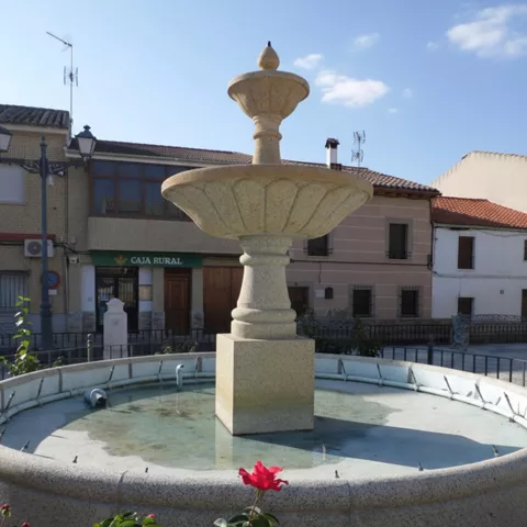 Fuente de piedra en plaza urbana con edificios al fondo