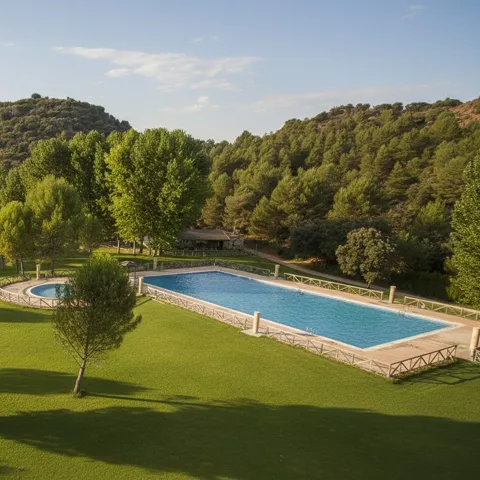 Piscina rectangular y piscina circular rodeadas de césped y arboleda.
