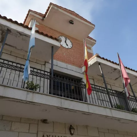 Fachada del ayuntamiento con reloj y banderas