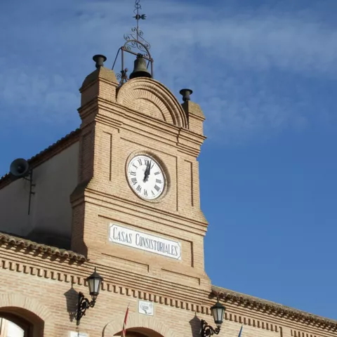 Torre de edificio histórico con reloj y campana sobre cielo azul