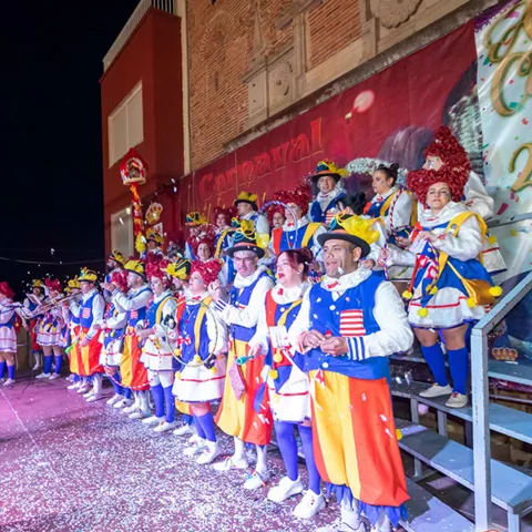 Grupo disfrazado cantando sobre un escenario nocturno