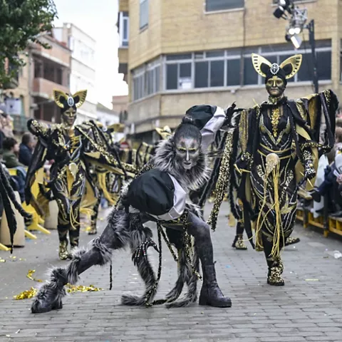 Grupo disfrazado con vestuario oscuro y máscaras teatrales