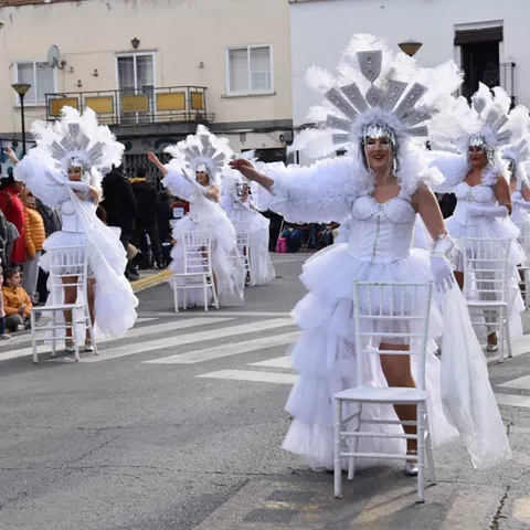 Bailarinas vestidas de blanco con plumas realizando una actuación coreografiada en la calle