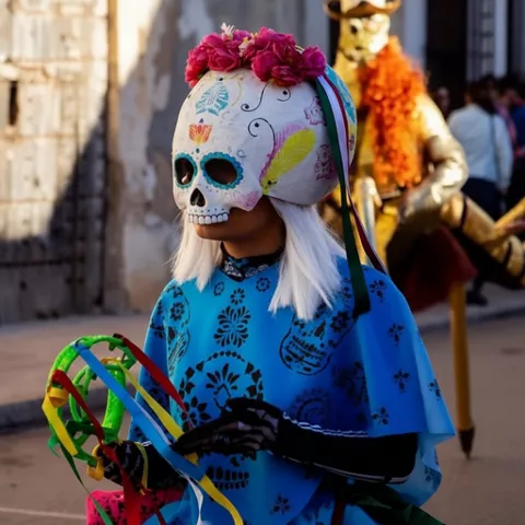 Persona con máscara de calavera decorada y traje colorido en desfile.