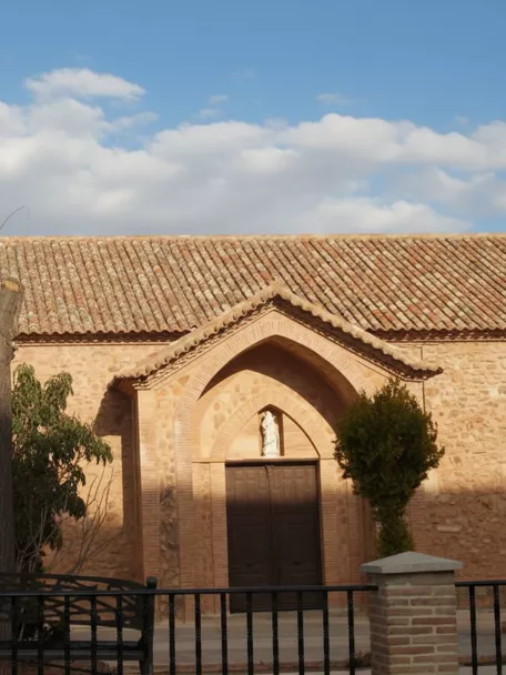 Iglesia parroquial de Carrizosa con torre campanario y portada de estilo tradicional en piedra y ladrillo.