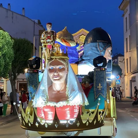 Carroza iluminada con figuras decorativas durante un desfile nocturno