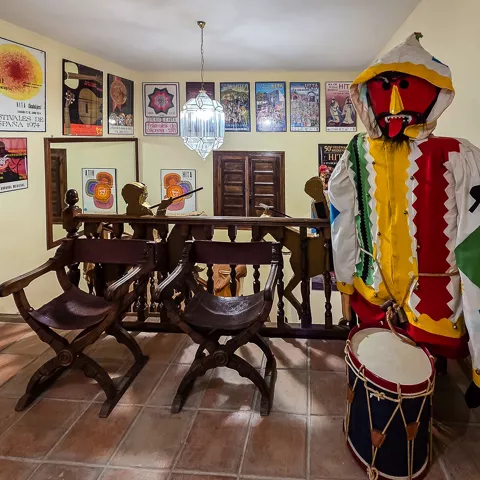 Sala expositiva con carteles enmarcados y figura con tambor.