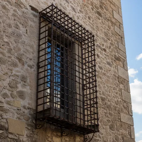 Ventana con reja de hierro sobre muro de piedra
