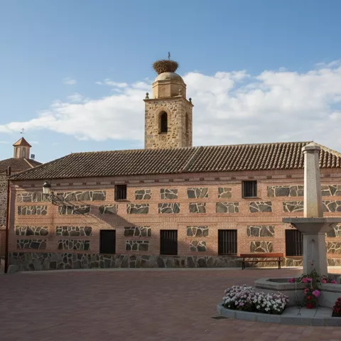Plaza con edificio histórico de piedra y torre con nido