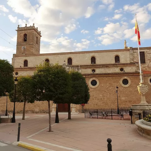 Fachada histórica con torre y arbolado urbano.
