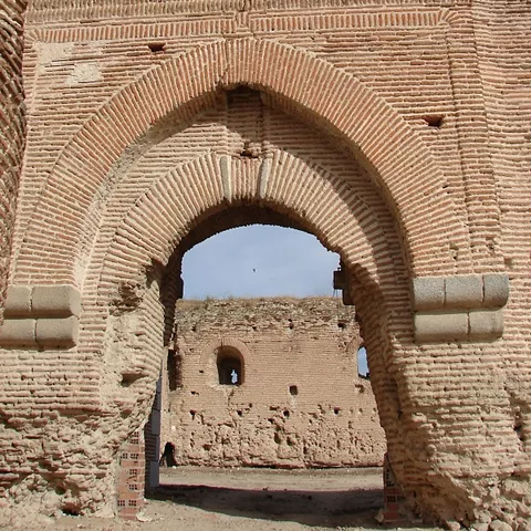 Interior de muralla con arco de ladrillo y escudos tallados