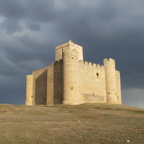 Castillo cuadrangular iluminado por cielo nublado.