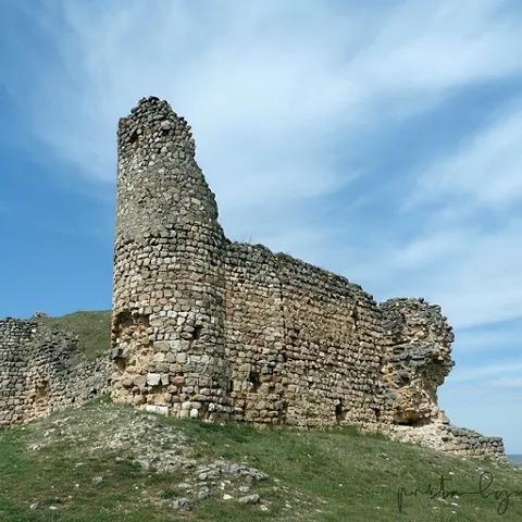Torre de piedra semiderruida bajo cielo nublado.