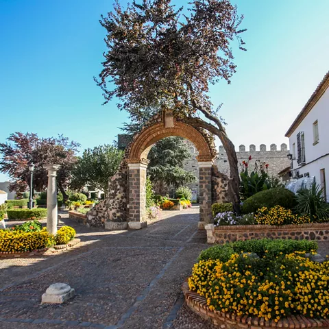 Arco histórico de acceso al recinto amurallado con flores.
