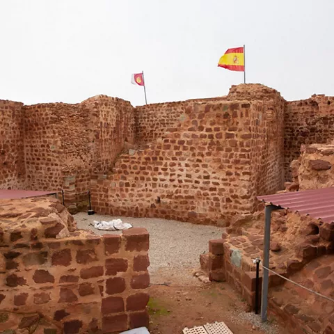 Recinto amurallado con torres de mampostería y banderas al fondo