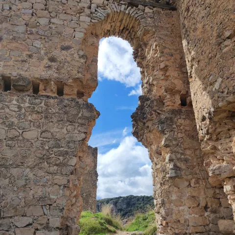 Arco de piedra abierto al paisaje natural.