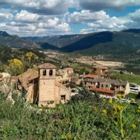 Vista panorámica de un pueblo de montaña rodeado de vegetación y colinas.