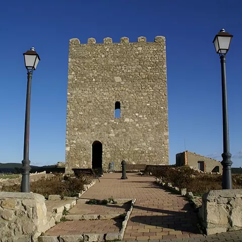Torre cuadrada de piedra junto a farolas.