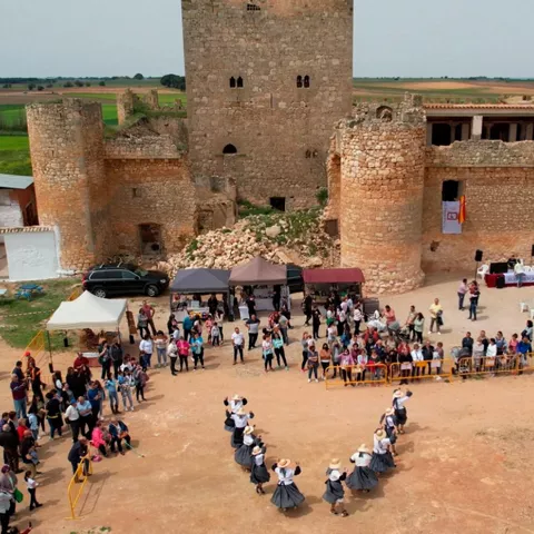 Castillo medieval con torres y baile tradicional frente a público.