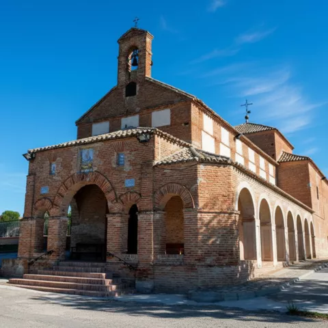 Iglesia de ladrillo con pórtico y torre campanario