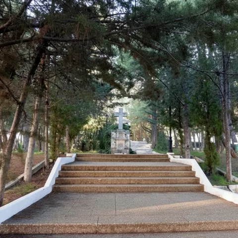 Escalinata con cruz en zona arbolada