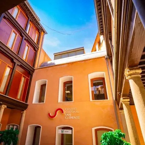 Patio interior con fachadas de colores, balcones de madera y columnas.