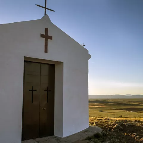 Pequeña ermita blanca sobre paisaje abierto
