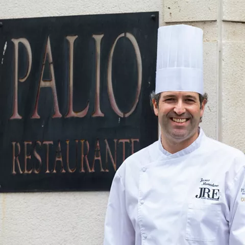 Chef sonriente junto a placa de restaurante