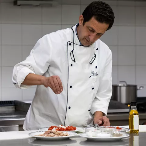 Cocinero aliñando ingredientes en cocina profesional