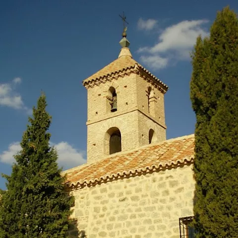 Espadaña de iglesia de piedra entre cipreses