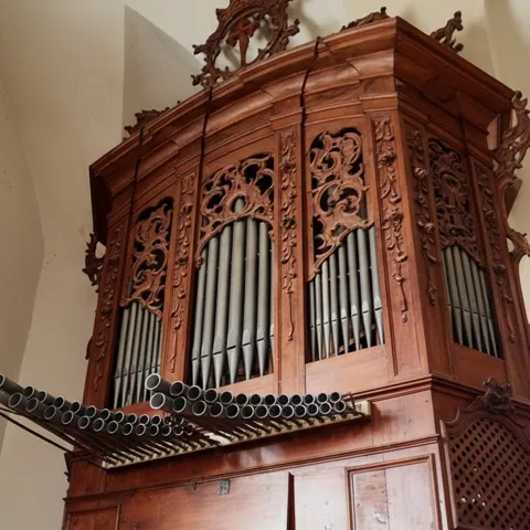 Órgano antiguo con caja de madera ornamentada y registros laterales.