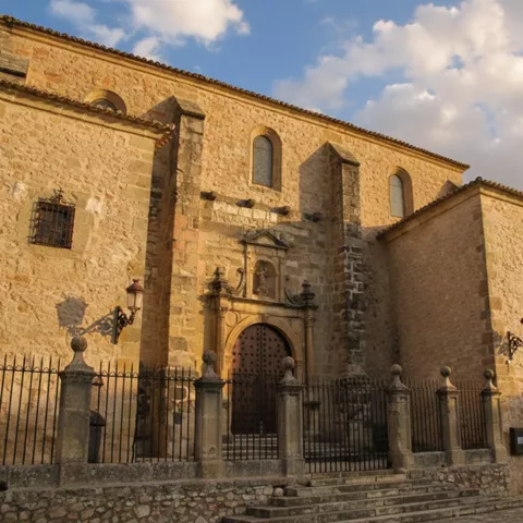 Fachada de iglesia de piedra con portada monumental y reja