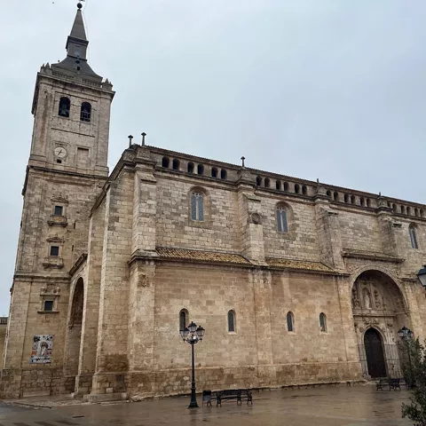 Fachada de gran iglesia de piedra con torre campanario