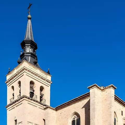 Campanario y portada de piedra bajo cielo azul intenso