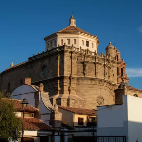Detalle exterior de una iglesia de piedra con cúpula y linterna bajo luz de tarde.