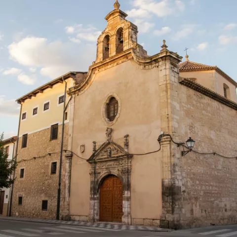 Fachada barroca con espadaña y puerta de madera.