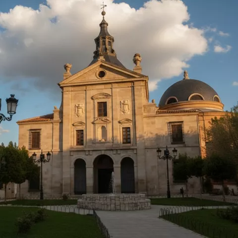 Fachada de iglesia iluminada al atardecer con cúpula y fuente frontal.