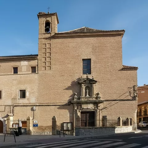 Fachada lateral de iglesia de ladrillo con pequeña espadaña y portada sencilla.