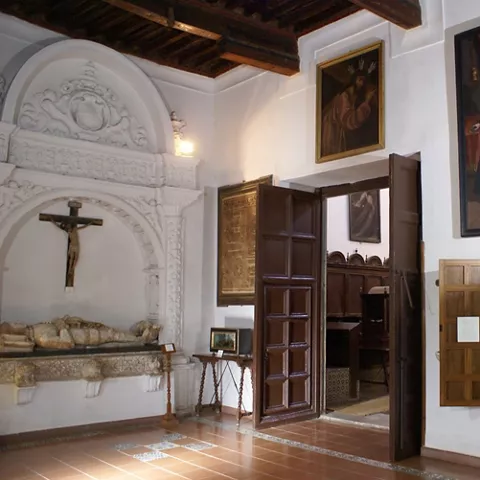 Sala con retablo, pinturas religiosas y techumbre de madera artesonada.