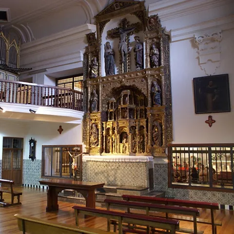 Coro con sillería de madera y retablo dorado al fondo.