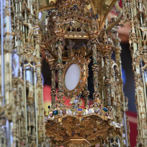 Detalle de una custodia dorada muy ornamentada con filigrana y un círculo central.