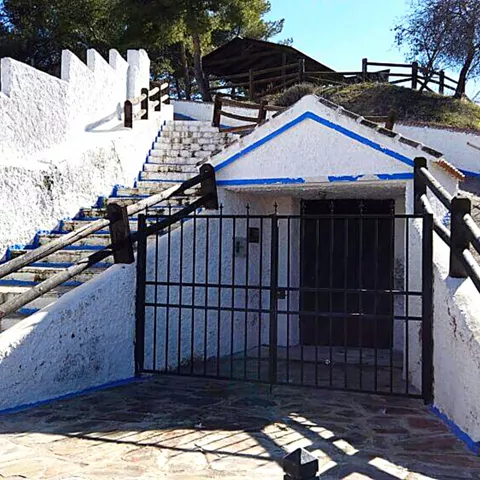 Escalera y entrada subterránea encalada con rejas negras y ribetes azules.