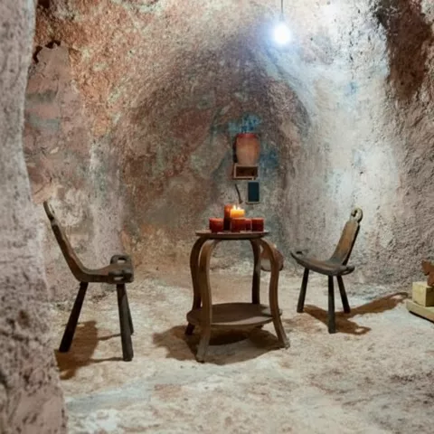 Sala excavada con mesa, sillas y velas.