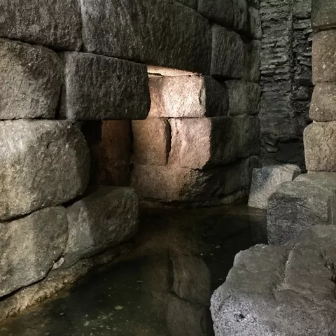 Canal de agua entre muros de piedra en un recinto subterráneo