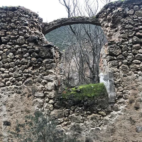 Arco de piedra entre restos arquitectónicos y árboles