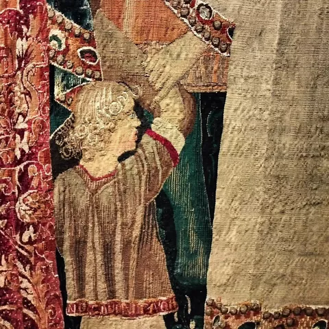 Detalle de tapiz medieval con figura sosteniendo estandarte